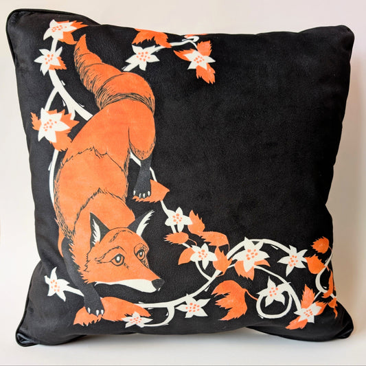 Decorative pillow with an orange fox and bramble linocut design on a black background